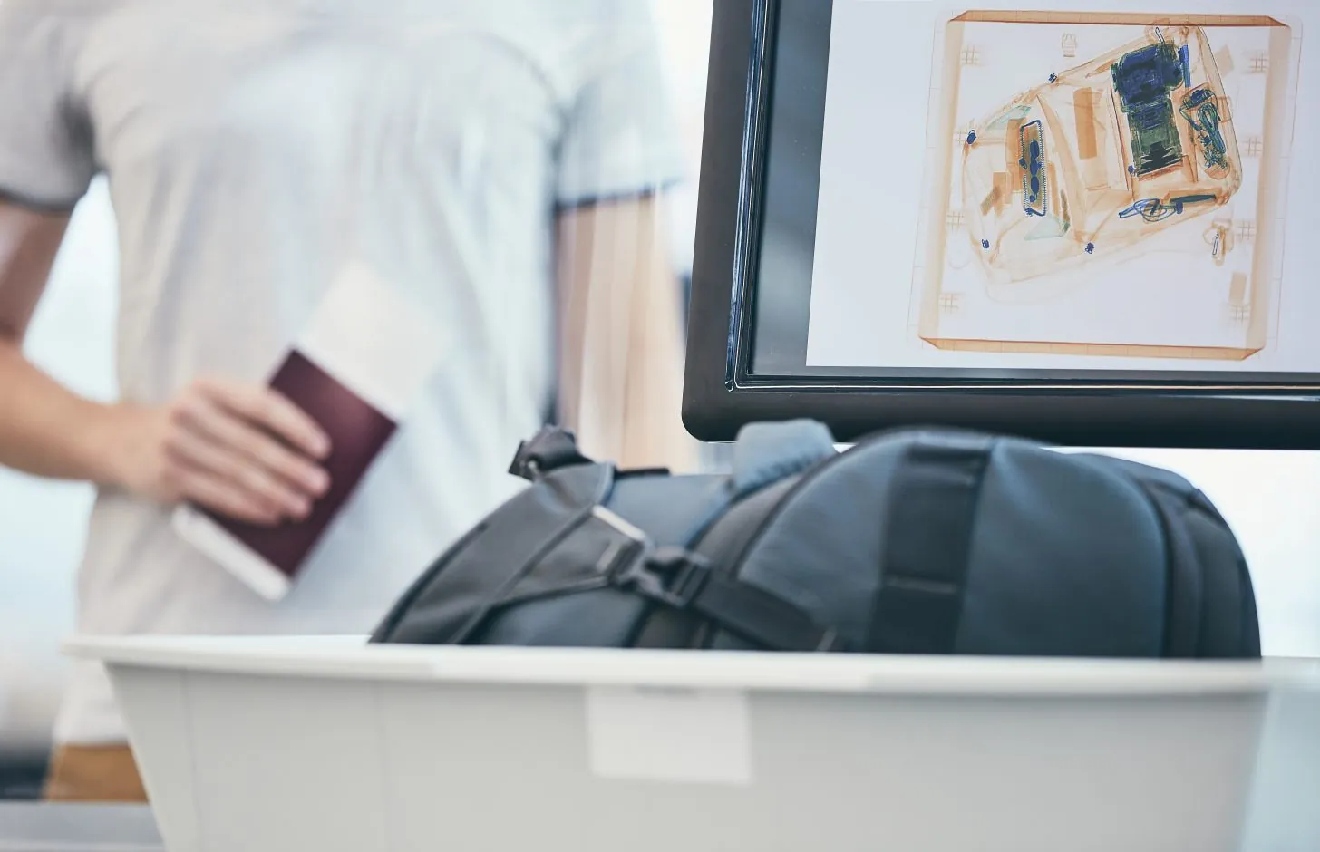 Airport security check. Young man holding passport and waiting for x-ray control his luggage.
